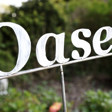 Schild "Oase" im Garten